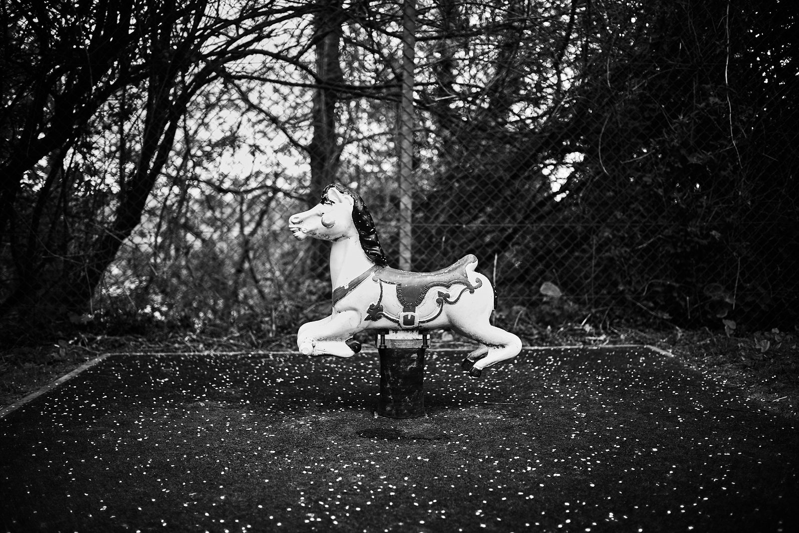 Abandoned rocking horse on derelict playground — black and white documentary photography