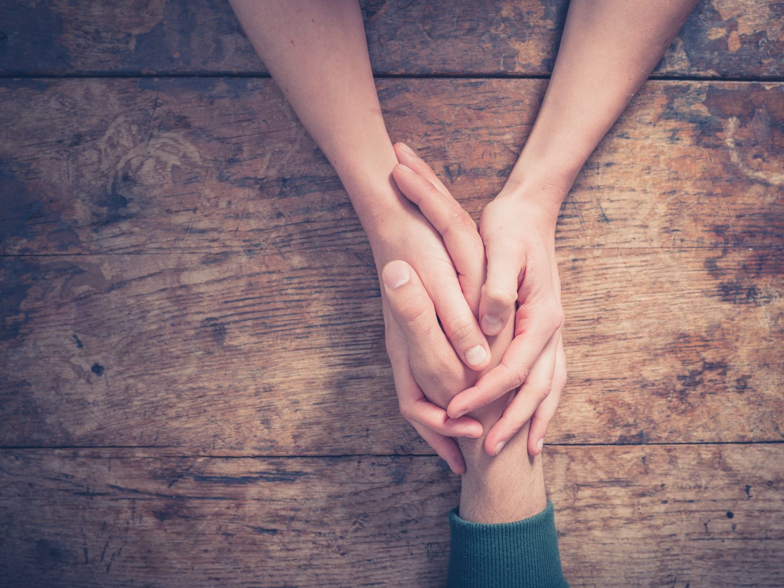 Couple holding hands on wooden table — intimate lifestyle photography